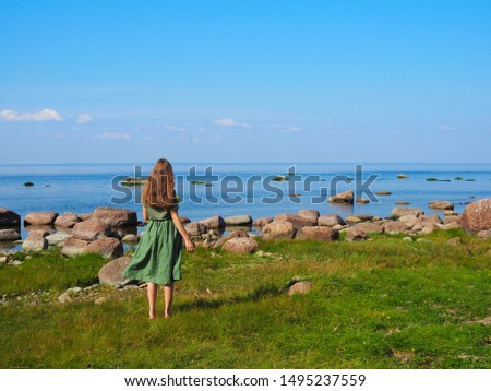 young beautiful girl happy in the background of the sea rear view