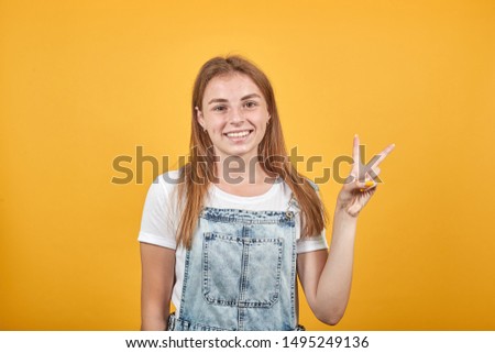 Young woman wearing white t-shirt, over orange background shows emotions