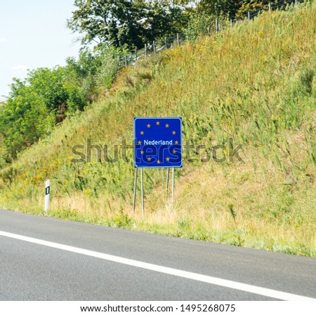 Nederland text at the border between Germany and Netherlands with text on the road sign with European union stars