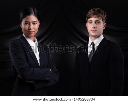 Diversity portrait of Asian and Caucasian Business man woman in dark blue Formal proper Suit, studio lighting black drape fabric background, Lawyer Boss act posing smile smart look profile