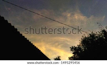 the sky in the afternoon, the color of the sky is almost dark, at night, plant silhouette, silhouette of the roof of the house