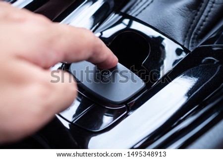 Hand push on electronic handbrake button in luxury modern car