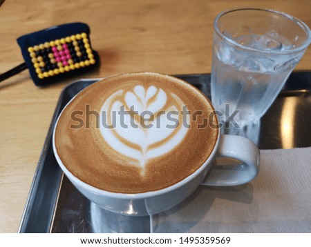 A cup of latte art coffee on table with alphabet letter "I love you" bead key chain 