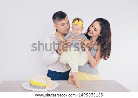 the child in the arms of his mother and father, who was soiled with food. A woman and man with a child in her arms eating cake