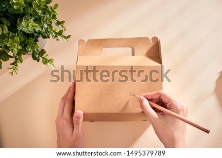 Cropped image of woman writing best wishes on box with present