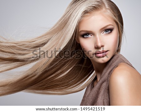 Face of the Beautiful young woman with long straight  hair - posing at studio over gray background