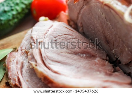 Homemade baked pork ham with aromatic herbs, cucumber and tomato. Festive traditional dish and Keto diet food. Selective soft focus. Text copy space. Ketogenic diet concept