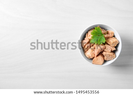 Bowl with canned tuna on light table, top view. Space for text Royalty-Free Stock Photo #1495453556