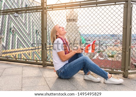 A young smiling girl sits on the floor against the background of the panorama of Vienna and against the background of the roof of St. Stephen's Cathedral in Vienna and enjoys the evening views of the
