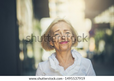 Value your age. Senior business woman standing on the street.