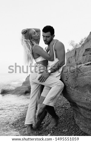fashion nlack and white outdoor photo of beautiful lovely couple wearing jeans,posing at summer beach