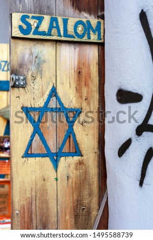 Szalom written on a wooden door. Jewish symbol, a blue Star of David hand painted on wood detail. Judaism star, judaist religion symbolism, texture. Jewish quarter shop front close detail