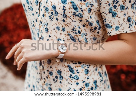 Street style, fashion, trendy summer woman`s outfit, details concept: white elegant wrist watch on hand with reptile textured leather strap, blue floral print dress Royalty-Free Stock Photo #1495598981