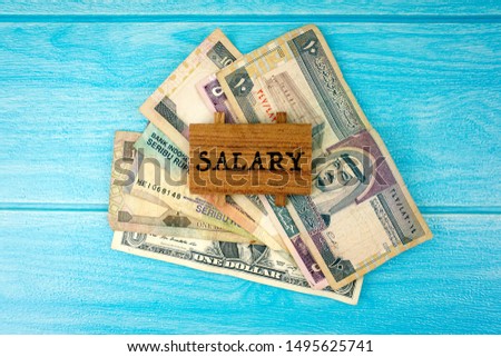 Salary words and banknotes over blue background.  Selective focus. 