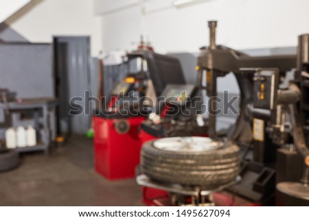 Blurred auto repair shop with tire changer and other machinery and equipment