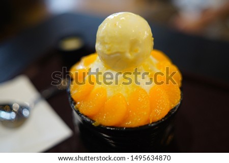 The selective focus of snowflake ice shaved bingsu kakigori with orange.