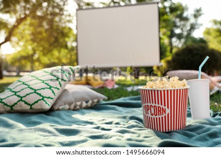 Popcorn and drink on blanket in open air cinema. Space for text