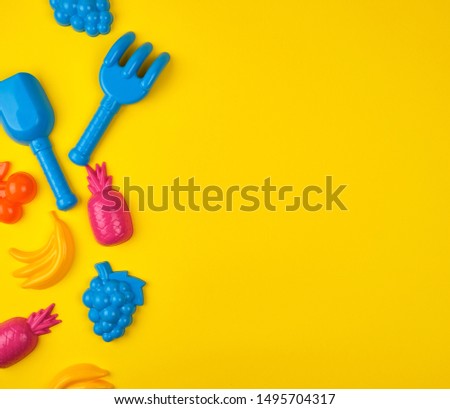 multicolored plastic toys fruits on a yellow  background, copy space , flat lay