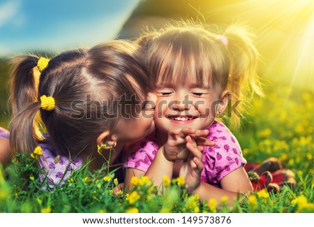 happy family. little girls twin sisters kissing and laughing in the summer outdoors