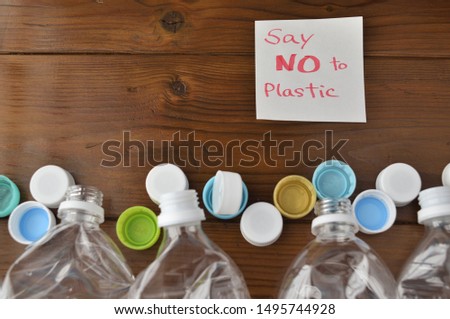 The words "Say NO to plastics" on memo paper with a lot of plastic bottle caps in top view.