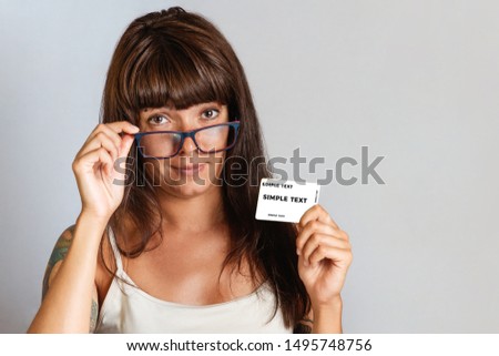 Finance and Bank cards. A young woman in glasses with tattoos on her hand holding a Bank card. Close up