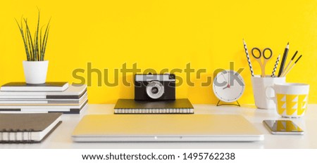Desk, school supplies near yellow background. Education, studying and back to school concept Creative desk with yellow wall and stationery.