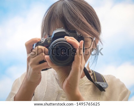 A woman taking picture from dslr camera with nice blue sky in the background.
