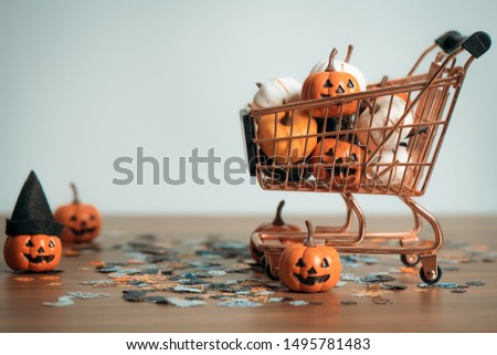 Discounted product at halloween holiday concept with with pumpkin Jack O'Lantern on cart and wooden table for background, design with copy space for text, advertising and banner.