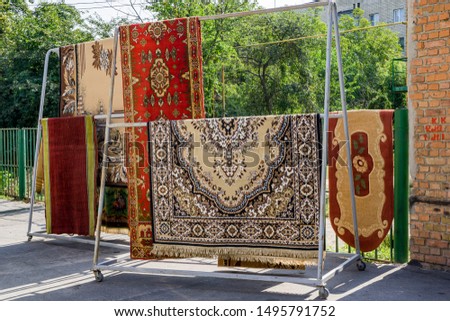 Different carpets hanging on rack outdoors. Professional carpet cleaning and drying. Royalty-Free Stock Photo #1495791752