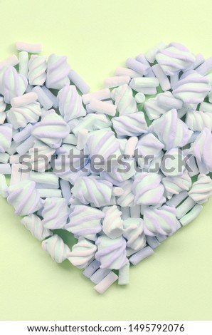 Colorful marshmallow laid out on lime and pink paper background. pastel creative textured heart
