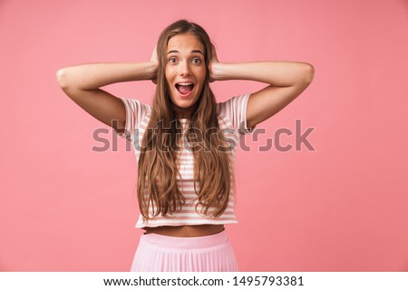 Picture of a happy surprised optimistic young girl posing isolated over pink wall background touching head.