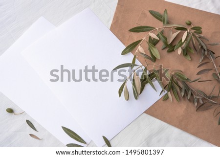 Minimalistic card mockup with olive branches. Flat lay, top view. Mockup card with plants. Wedding invitation card with environment and details