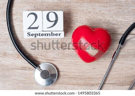 September 29 of white calendar and Stethoscope with Red heart shape on wooden background. Healthcare, life Insurance and World Heart Day concept