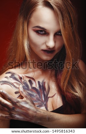 Halloween girl vampire with red eyes red lips and red background. Scary woman trick or treat time, halloween concept. Female costume for holiday with old rose in the mouth