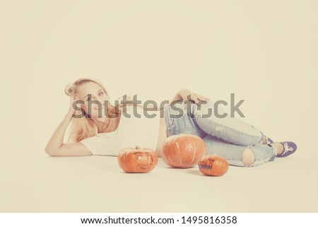 Halloween concept, happy Girl lies on floor with pumpkins preparing for holiday, with Jack lantern, funny and spooky pumpkin. Trick or treat tradition. 