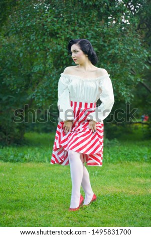 Vintage portrait of a woman in retro white and red dress in the city park