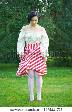 Vintage portrait of a woman in retro white and red dress in the city park