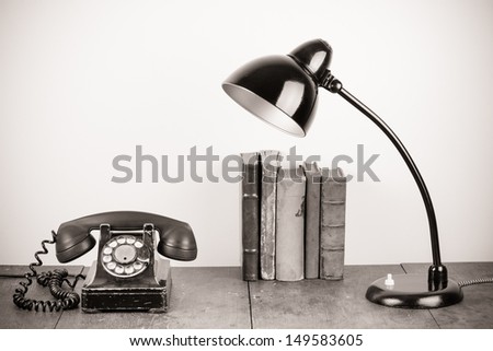 Old rotary telephone, desk lamp, vintage books on table still life