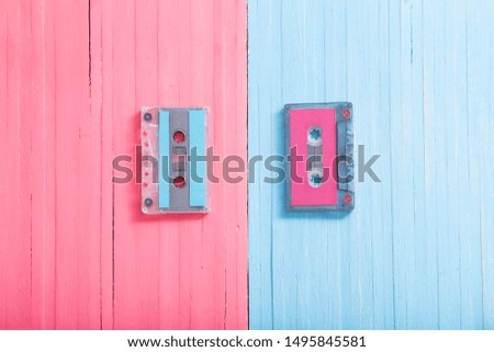 Old plastic cassette on pink and blue wooden background. Retro music concept