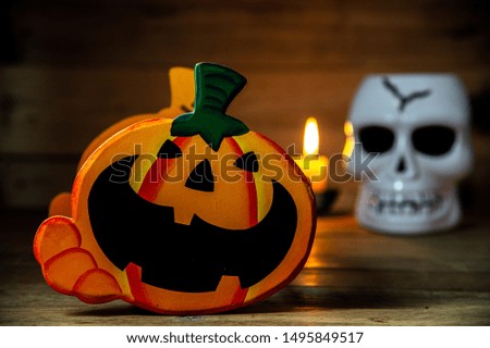 Happy Halloween, main focus Jack O Lantern halloween pumpkin  with scary skull and candle on blur  wooden background