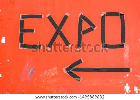 expo sign made of black isolation tape on a worn down orange background