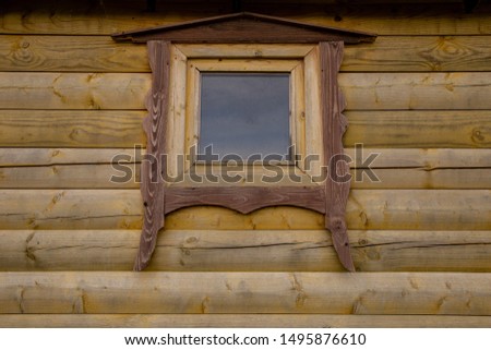 a small window in a beige wooden building. Timber cylinder
