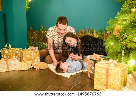 portrait of a young family near the Christmas tree. Happy smiling young family near the Christmas tree. Celebrate New Year. Mom dad and kid at Christmas tree. Mother father and child on Christmas Eve