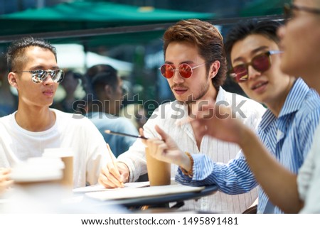 young asian college students having a group discussion at an outdoor coffee shop