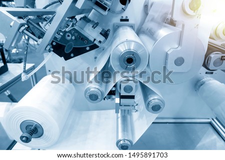 The operation of automatic plastic bag production machine with lighting effect. Close-up of the roller of the plastic bag production machine in the light blue scene. Royalty-Free Stock Photo #1495891703