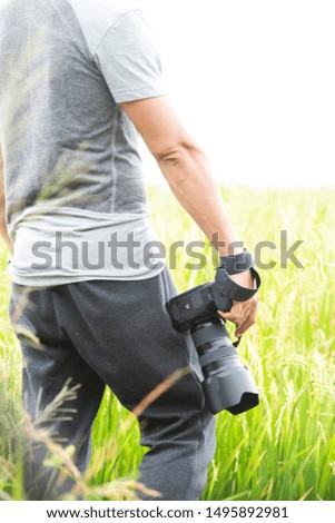 Man photography concepts. Young Asian professional photographer working camera on paddy field. - Image