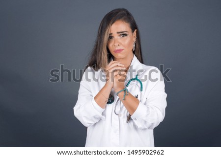 Sad pretty doctor girl feeling upset while spending time at home alone. Beautiful young female with long hair staring at camera with unhappy or regretful look standing outdoors.