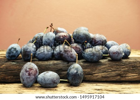 Beautiful fresh blue plums on old oak wooden table and brown wall background.
