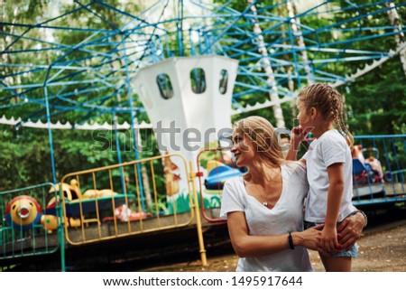 Loving each other. Cheerful little girl her mother have a good time in the park together near attractions.