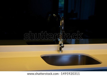 Modern faucet at the kitchen room stainless reflection on black background